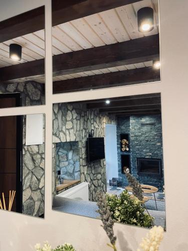 a room with a stone wall with a table and a tv at Mount House Mavrovo in Mavrovo