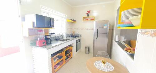 Una pequeña cocina con nevera y mesa. en Sobrado no Melhor Local do Indaiá, en Caraguatatuba