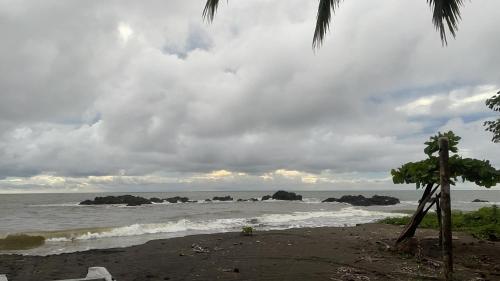 a beach with rocks in the ocean on a cloudy day at Posadas el Nativo in Bahía Solano