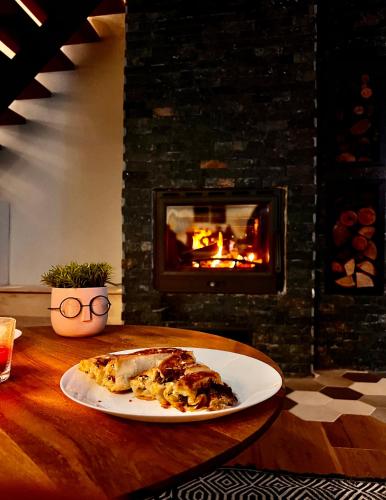 a slice of pizza on a plate on a table with a fireplace at Mount House Mavrovo in Mavrovo