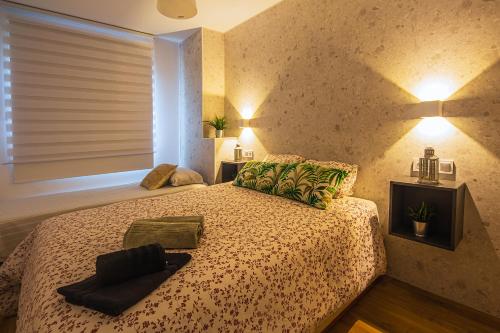 Un dormitorio con una cama con almohadas verdes y una ventana en CARTAGENAFLATS, Apartamentos Anfiteatro Romano 4B en Cartagena