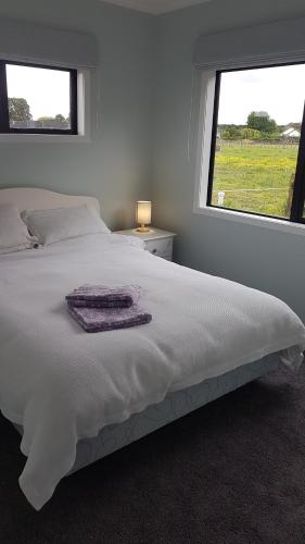1 dormitorio con 1 cama blanca grande y ventana en Aberdeen Cottage with Hobbit House sleep-out, en Tamahere