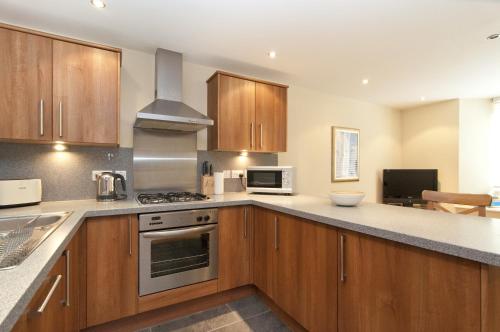 a kitchen with wooden cabinets and a stove top oven at Edinburgh Church Apartments in Edinburgh