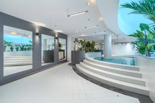 a lobby with a swimming pool and stairs and plants at Hotel Hanza Tower 5 Stars in Szczecin
