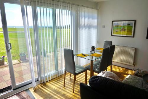 sala de estar con mesa y sillas y balcón en SEAVIEW self-catering coastal bungalow in rural West Wight en Freshwater