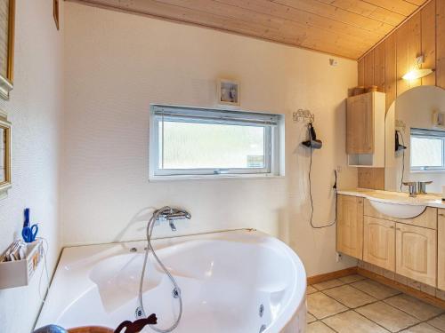 a bathroom with a white tub and a sink at 8 person holiday home in R dby in Rødby