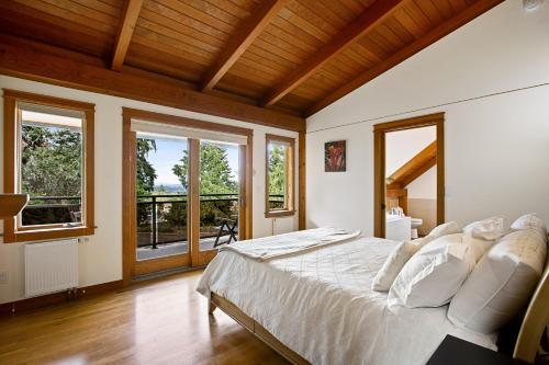 a bedroom with a large bed in a room with windows at Bainbridge Island Timber Retreat in Fort Ward