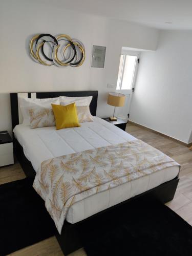 1 dormitorio con 1 cama blanca grande con almohadas amarillas en Casa da Avó Biza en São Roque do Pico