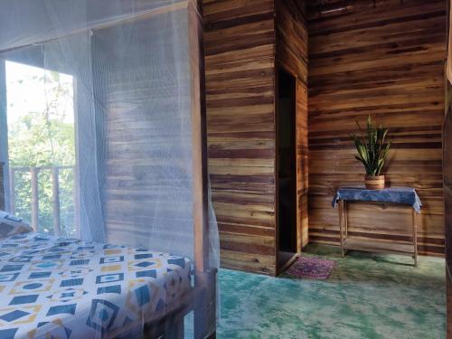 Schlafzimmer mit Holzwänden, einem Bett und einem Fenster in der Unterkunft Hostal Corazón de Tagua in Palomino