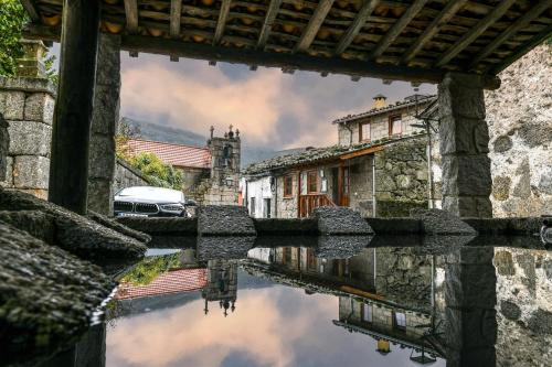 a reflection of a building in a body of water at Casa do Tio Ferreiro in Sabugueiro