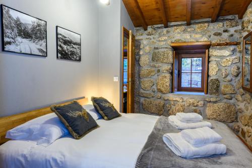 a bedroom with two beds and a stone wall at Casa do Tio Ferreiro in Sabugueiro