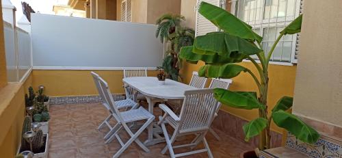 una mesa y sillas en una habitación con una planta en BUNGALOW CON ENCANTO, MONTE DE MAR, en Gran Alacant