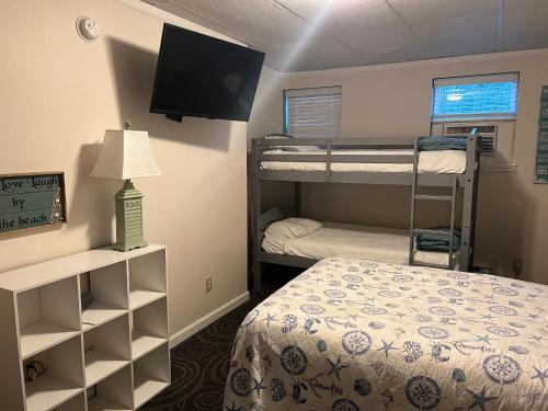 a room with two bunk beds and a television at Carbone's Beachside Guest Rooms in Sylvan Beach