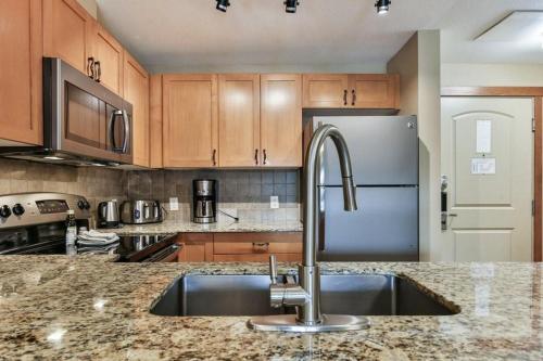 a kitchen with a sink and a refrigerator at B&B Falcon Crest Lodge 1BR 1Pullout in Canmore