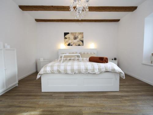 Habitación blanca con cama y lámpara de araña. en charming apartment with fireplace, en Zarchlin