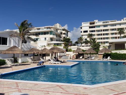 una piscina con sillas, sombrillas y edificios en Condominios Brisas, en Cancún