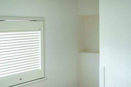 a window with blinds on a white wall at Sensui in Toyooka