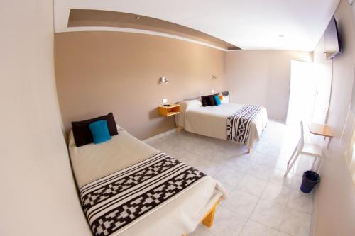 een kleine kamer met 2 bedden en een raam bij Amigo del Mundo Hostería y Apart Hotel in El Calafate