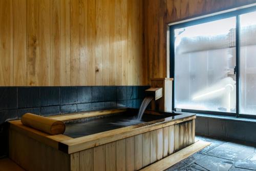 a hot tub in a room with a window at Sensui in Toyooka