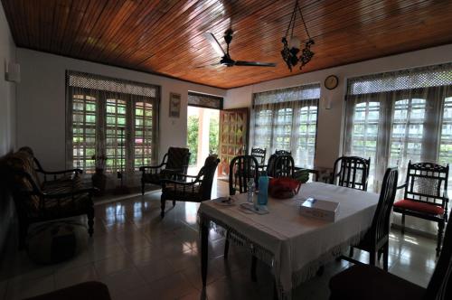 a dining room with a table and chairs and windows at SYDNEY HOMESTAY in Hikkaduwa