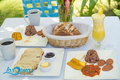 a table with plates of food and a basket of bread at Las Dunas Surf Resort in Aposentillo