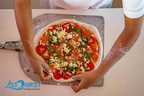 a person is making a pizza on a counter at Las Dunas Surf Resort in Aposentillo