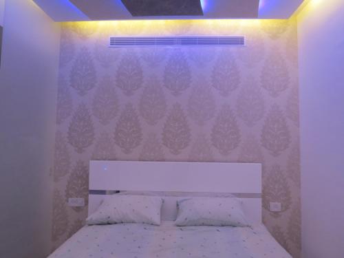 a bedroom with a white bed with a wall at Apartment Ben Gurion in Bat Yam