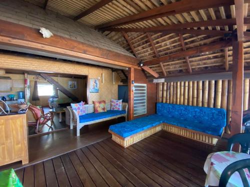 a living room with a blue couch and wooden floors at Beach de rêve de moorea in Hauru