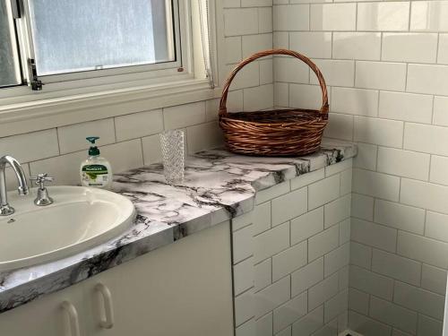 a bathroom with a sink and a basket on a counter at Cheerful 2 bedroom house with a beautiful veranda in Geelong
