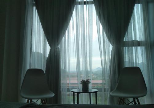 um quarto com 2 cadeiras e uma grande janela em Armada Sweet Homestay em Gua Musang