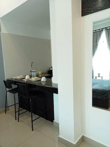 a kitchen with a black table and chairs and a bed at Armada Sweet Homestay in Gua Musang