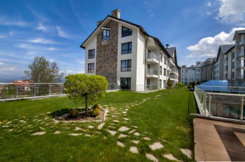 a building with a yard with a tree in front of it at Saint George Palace Aparthotel in Bansko
