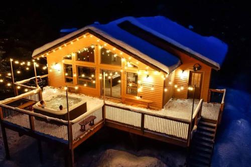 una baita di tronchi con luci nella neve di notte di Le Chic Harfang Mont Tremblant a Lac-Superieur