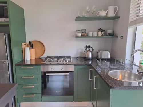 a kitchen with green cabinets and a stove and a sink at Oak Village in Stellenbosch