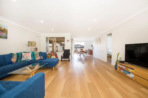 a living room with a blue couch and a television at Wagtails Pet Friendly 10 Mins Walk to Beach in Culburra Beach