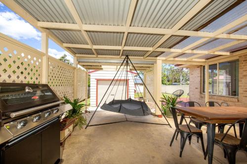 a screened porch with a table and a swing at Wagtails Pet Friendly 10 Mins Walk to Beach in Culburra Beach