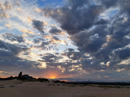 a sunset on the beach with a cloudy sky at Penthouse at Casa Esda in Jeffreys Bay