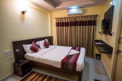 a bedroom with a bed and a tv on the wall at HOTEL PRAKAASH COMFORTS in Vānivilāsa Puram