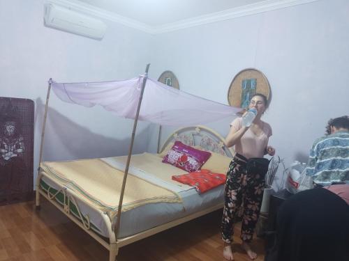 a shirtless man standing next to a bed at Phonluer Angkor Homestay, in Siem Reap