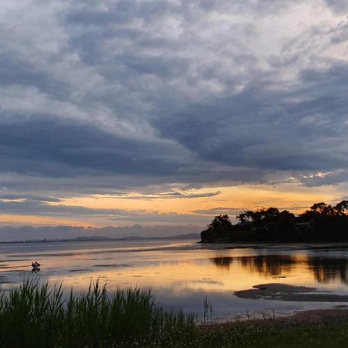 a sunset over a body of water with a boat in it at Tuggerah lakefront 4 bed 2 bath home with stunning views in Gorokan