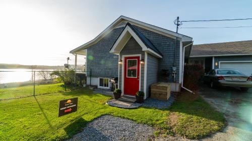 a small house with a red door in a yard at Sunset Tides in Oak Haven