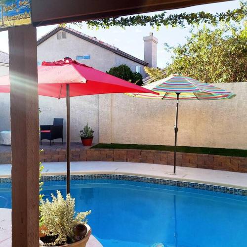 two umbrellas sitting next to a swimming pool at New beautifully remodeled home in Las Vegas in Las Vegas