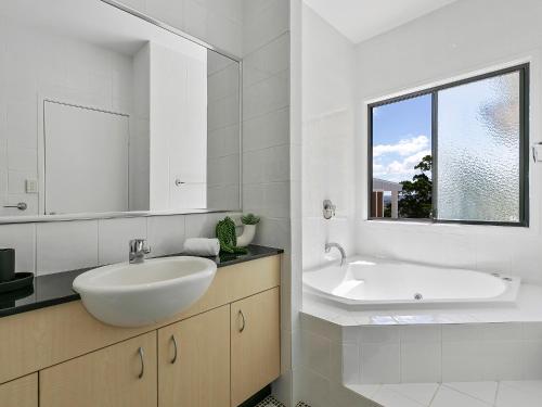 a white bathroom with a sink and a mirror at Noosa Dreaming in Noosa Heads