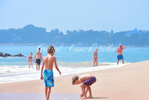 two boys playing in the water on the beach at Conch Villa in Tangalle