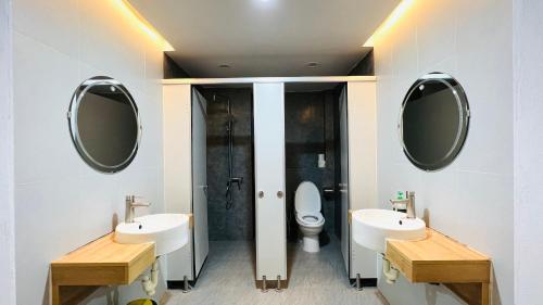 ein Badezimmer mit zwei Waschbecken, einem WC und zwei Spiegeln in der Unterkunft The Hive Homestay in Hanoi