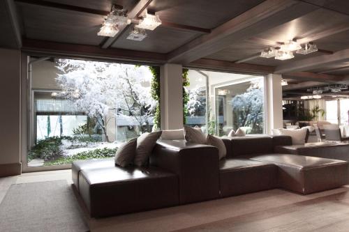 a living room with a couch and large windows at Palace Hotel Wellness & Beauty in Bormio