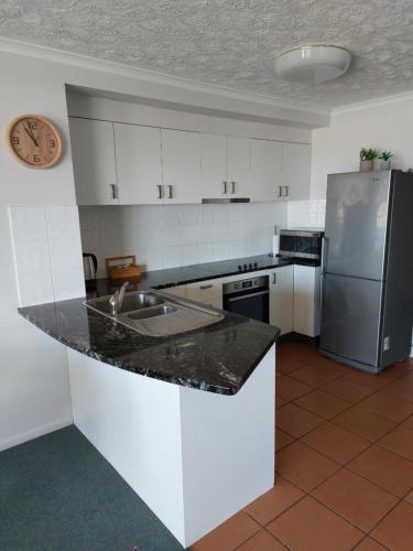 a kitchen with white cabinets and a stainless steel refrigerator at Sandy Shores Holiday Units in Caloundra