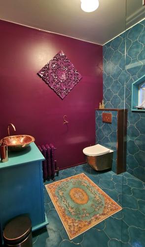 a bathroom with a sink and a toilet and purple walls at Wonderland in Pieterburen