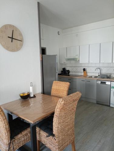 une cuisine avec une table et des chaises en bois ainsi qu'une horloge dans l'établissement Nid Douillet, à Rochefort