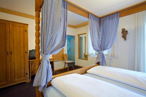 a bedroom with a bed with blue curtains at Hotel B&B Pardeller in Nova Levante